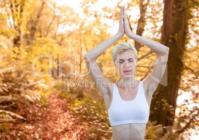 Woman meditating against blurry forest