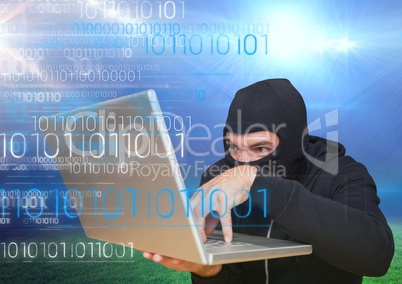 Hacker using a laptop in front of grass field