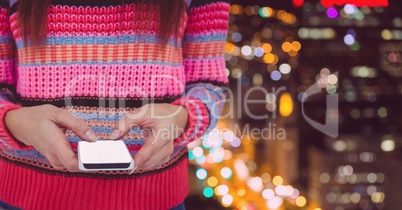 Part of a woman texting against buildings in background