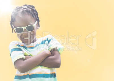 Boy in sunglasses arms folded against yellow background with flare