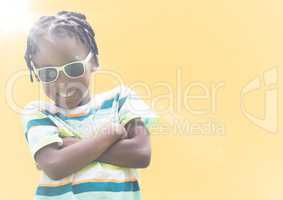 Boy in sunglasses arms folded against yellow background with flare