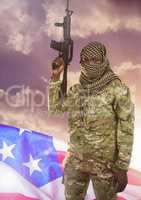 Soldier with weapon in front of american flag and clouds