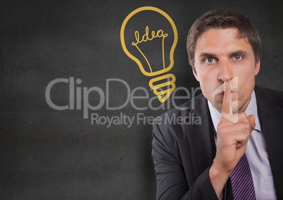Business man finger on mouth against grey wall with yellow lightbulb graphic