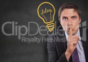 Business man finger on mouth against grey wall with yellow lightbulb graphic