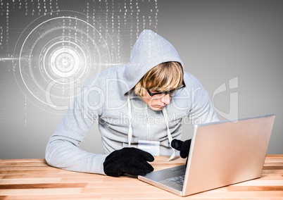 Blond-hair hacker using a laptop on wood table in front of grey background