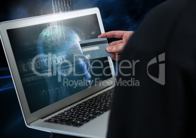 Hacker holding a credit card and using a laptop with 3D digital face on screen