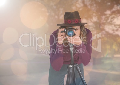 photographer with hat taking a photo with tripod  in the park. Lights and flares