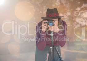 photographer with hat taking a photo with tripod  in the park. Lights and flares