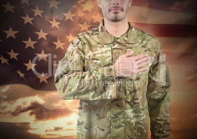 Military with hand on his heart against sunset and american flag