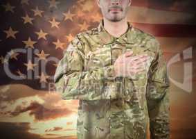 Military with hand on his heart against sunset and american flag