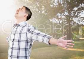 Man with arms outstretched against blurry park with flare