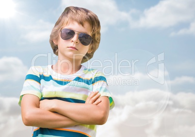 Boy in sunglasses arms folded against sky with flare