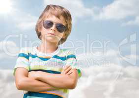 Boy in sunglasses arms folded against sky with flare