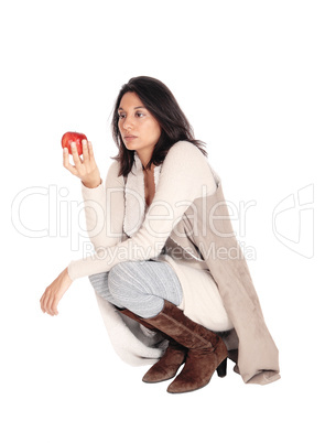 Woman crouching looking at a red apple.