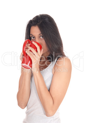 Hispanic woman drinking from a red mug.