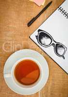 Sunglasses doodle on notepad next to tea