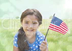 Girl with american flag against meadow with flare