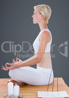 Woman meditating with candles against grey background