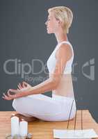 Woman meditating with candles against grey background