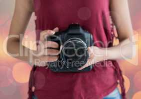 photographer hands with camera. Pink and yellow blurred lights.