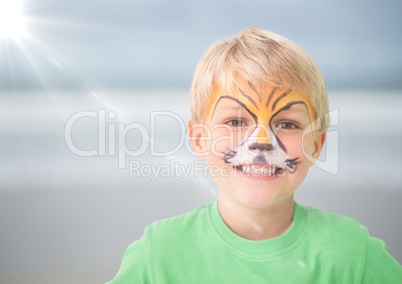 Boy with tiger facepaint against blurry beach with flare