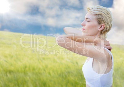 Woman stretching against blurry meadow on summer day with flare