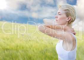 Woman stretching against blurry meadow on summer day with flare