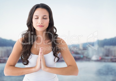 Woman meditating against blurry skyline