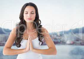 Woman meditating against blurry skyline