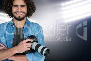 Smiling man with camera on his hands on spotlight background