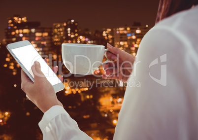Part of a woman texting while having a coffee with buildings in background