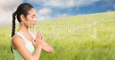 Woman meditating against blurry meadow on summer day
