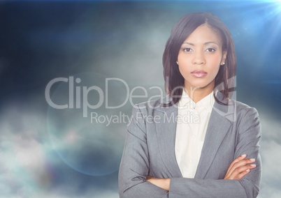 Business woman arms folded against clouds and flares