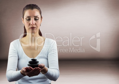 Woman meditating with stones against pink wall