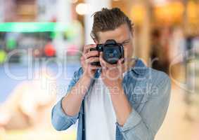 young photographer taking a photo. Store blurred lights background