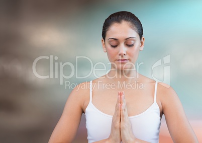 Woman meditating against blurry blue brown background