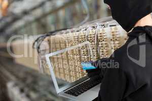 Hacker using a laptop in a data center