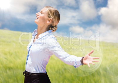 Business woman arms outstretched against blurry meadow on summer day with flare