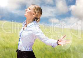 Business woman arms outstretched against blurry meadow on summer day with flare