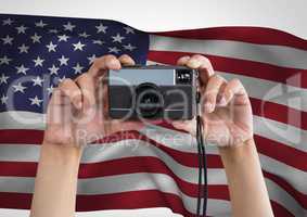 Hands of a photographer taking picture against american flag