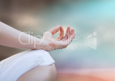 Hand and knee of meditating woman against blurry blue brown background