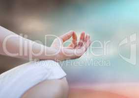 Hand and knee of meditating woman against blurry blue brown background