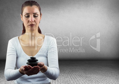 Woman meditating with stones against grey wall