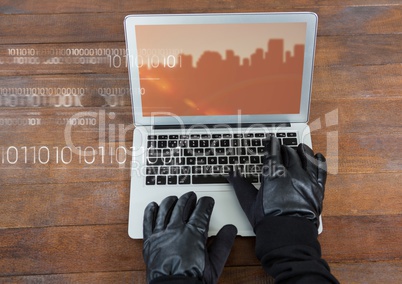 Hands typing on laptop with a screen with city buildings on wood table