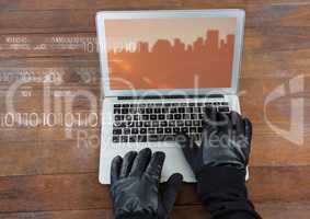 Hands typing on laptop with a screen with city buildings on wood table