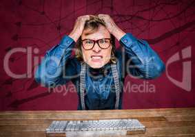 Frustrated business man at desk against maroon background and arrow graphics