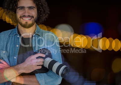 Smiling Photographerholding a camera against glowing background