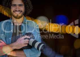 Smiling Photographerholding a camera against glowing background