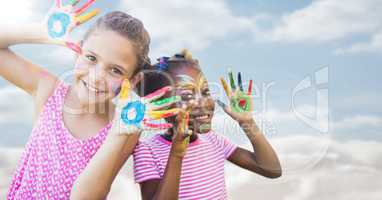 Girls with paint on hands against sky with flare