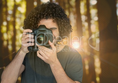 photographer taking a photo on forest with flare behind and blurred lights overlap.